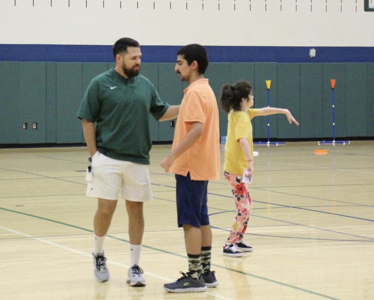 Coach Gonzalez teaching a partners PE student how to throw a football. This year is Gonzalezs first year at Reedy.
