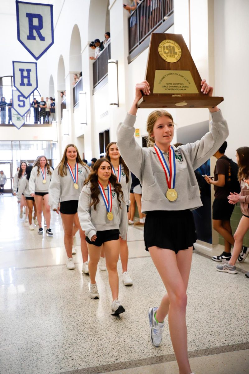 Girls+swim+and+dive+team+walking+in+to+the+school+holding+up+their+trophy.+This+is+only+the+ninth+time+in+history+that+a+FISD+team+has+won.